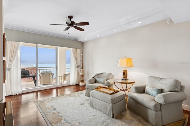 living area with dark hardwood / wood-style floors, ceiling fan, a water view, and crown molding