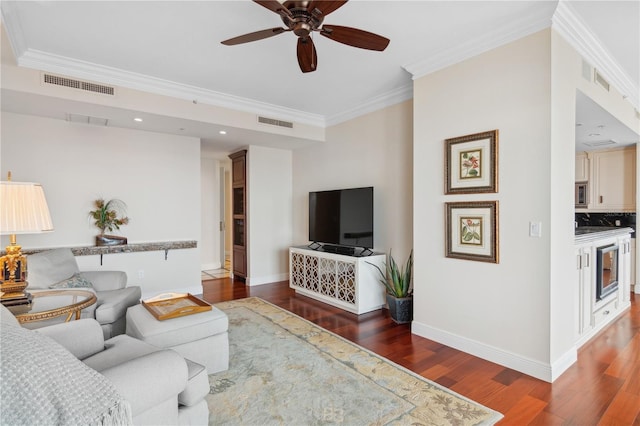 living room with ornamental molding, ceiling fan, and dark wood-type flooring