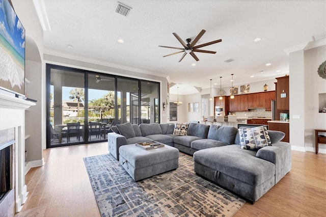 living room with hardwood / wood-style floors, ceiling fan, ornamental molding, and a fireplace