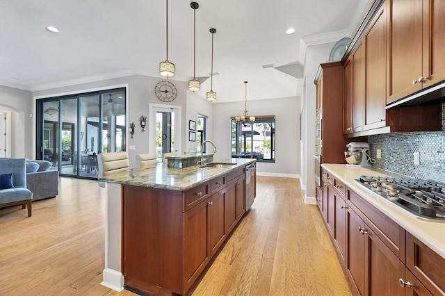 kitchen with sink, stainless steel appliances, decorative light fixtures, and light wood-type flooring