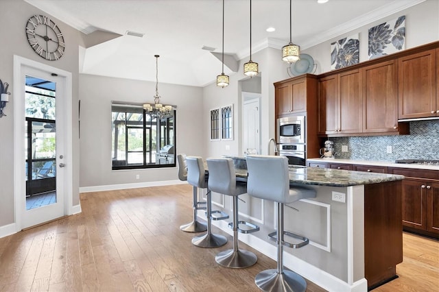 kitchen with hanging light fixtures, a kitchen island with sink, light hardwood / wood-style flooring, and stainless steel appliances