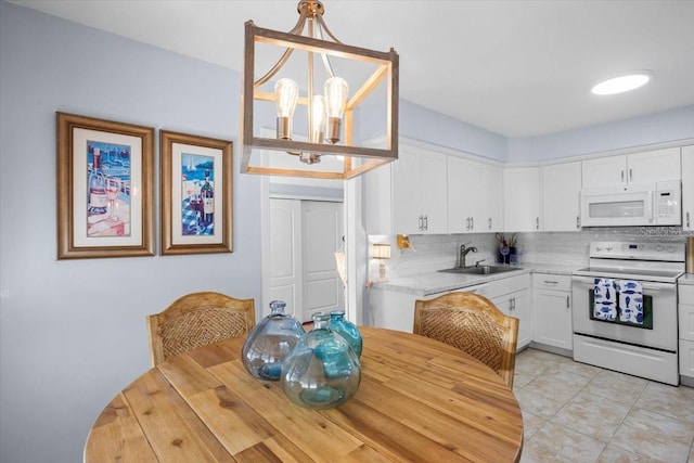 kitchen with sink, decorative light fixtures, white cabinets, white appliances, and a chandelier