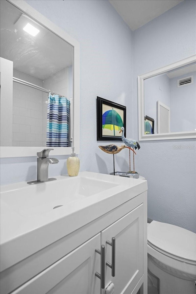 bathroom with a shower with shower curtain, vanity, and toilet