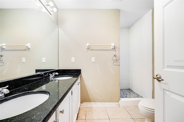 bathroom featuring tile patterned flooring, vanity, toilet, and tiled shower