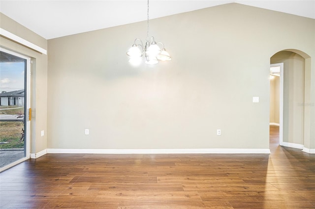 empty room featuring hardwood / wood-style flooring, a chandelier, and vaulted ceiling