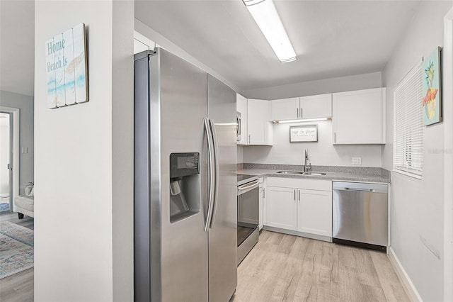 kitchen with white cabinets, sink, stainless steel appliances, and light hardwood / wood-style flooring