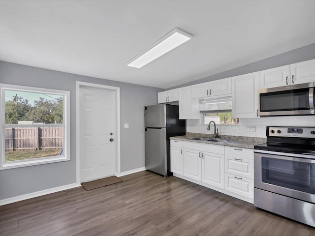 kitchen with sink, dark hardwood / wood-style floors, appliances with stainless steel finishes, light stone counters, and white cabinetry