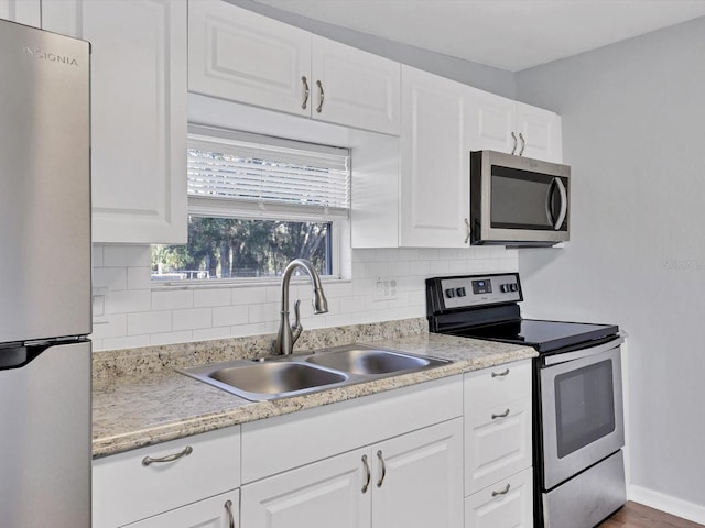 kitchen with decorative backsplash, appliances with stainless steel finishes, white cabinetry, and sink