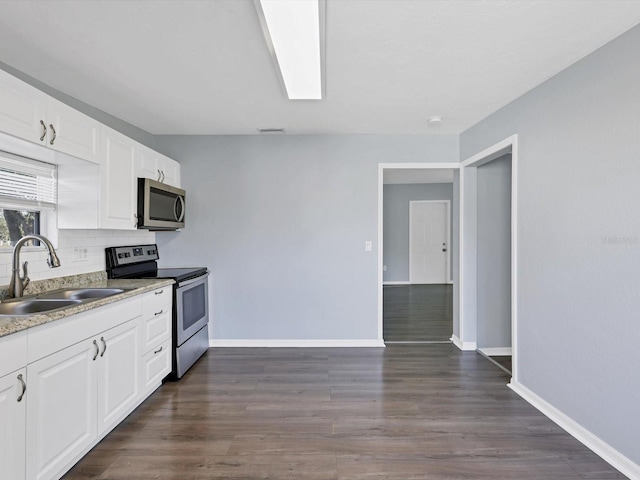 kitchen with appliances with stainless steel finishes, dark hardwood / wood-style flooring, white cabinetry, and sink