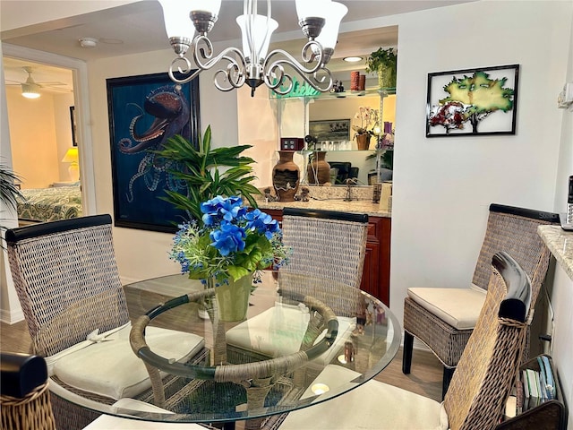 dining room with bar area, hardwood / wood-style floors, and ceiling fan with notable chandelier