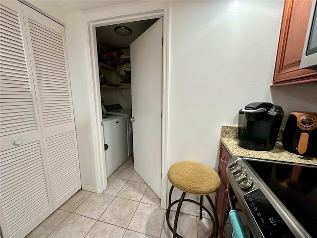 kitchen featuring stainless steel electric stove, light tile patterned floors, and independent washer and dryer