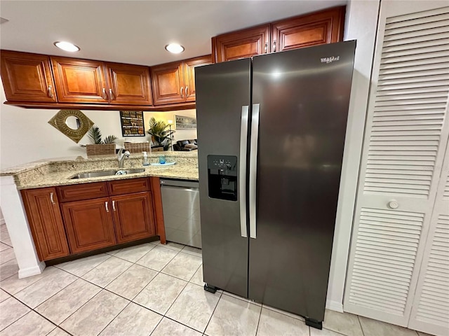 kitchen with kitchen peninsula, appliances with stainless steel finishes, light stone counters, sink, and light tile patterned floors