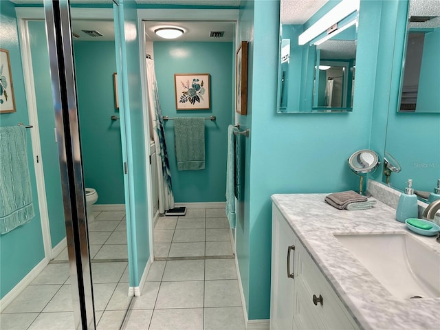 bathroom featuring tile patterned floors, vanity, toilet, and a textured ceiling