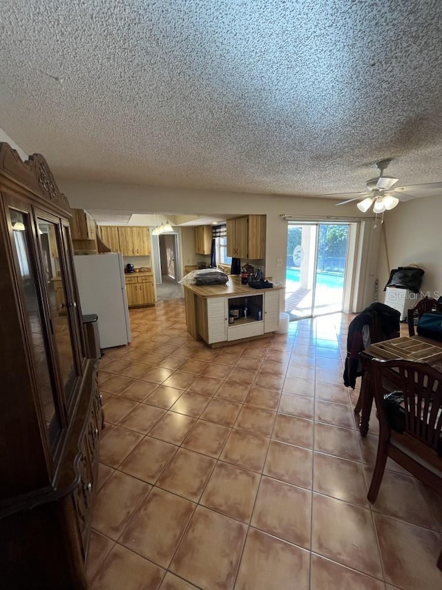 kitchen featuring ceiling fan, white refrigerator, and a textured ceiling