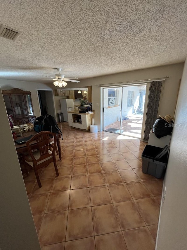 tiled dining room with ceiling fan and a textured ceiling