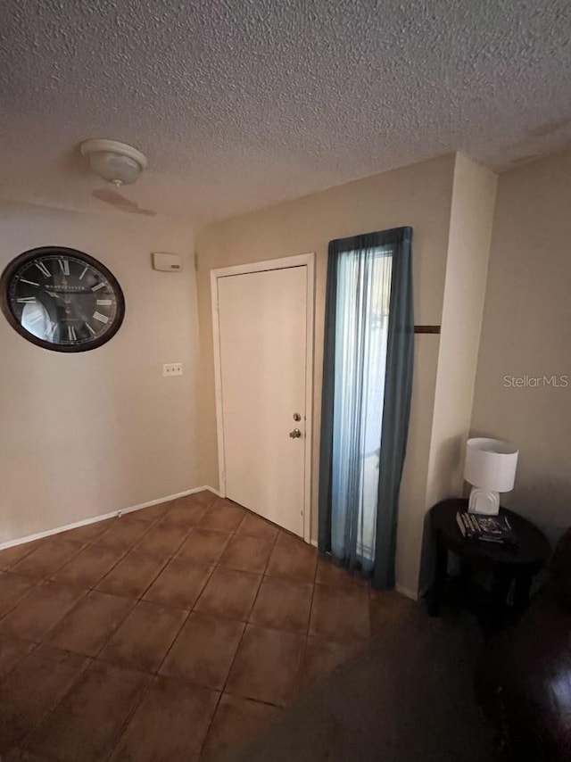 entrance foyer with dark tile patterned floors and a textured ceiling