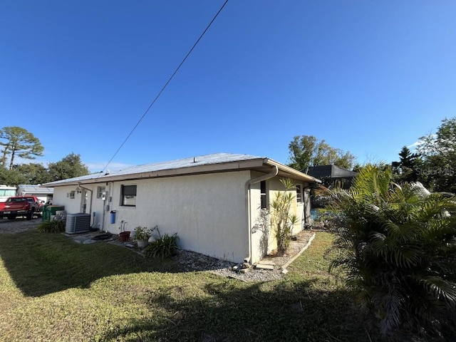 view of side of property featuring a yard and central AC