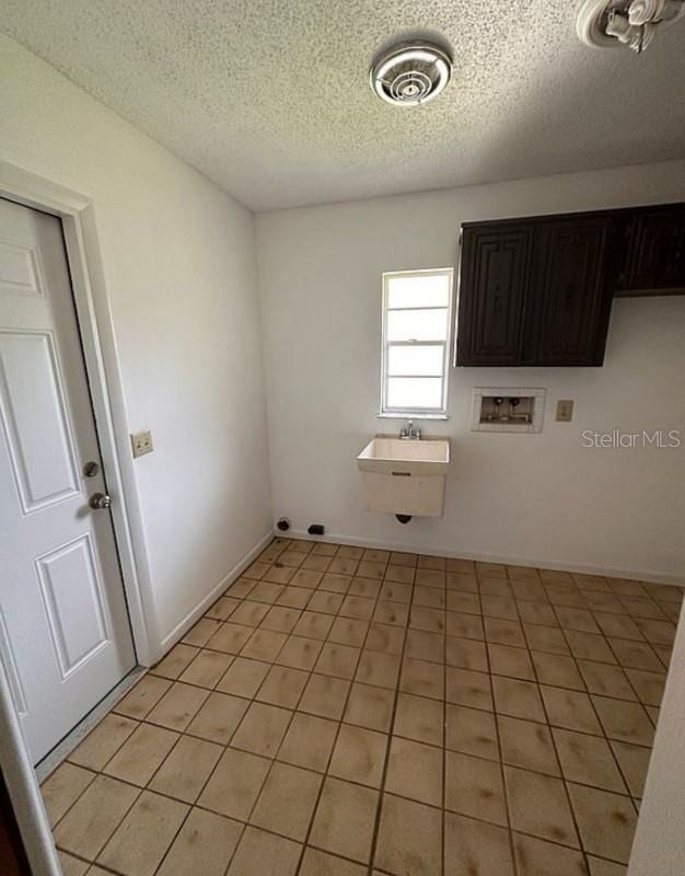 washroom featuring cabinets, washer hookup, a textured ceiling, and light tile patterned flooring