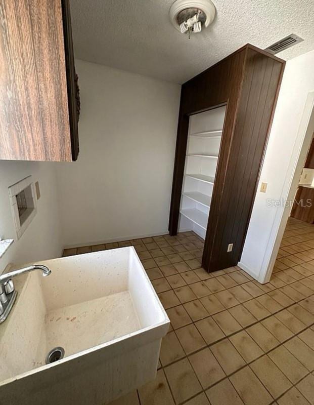 bathroom featuring tile patterned floors, a bath, sink, and a textured ceiling