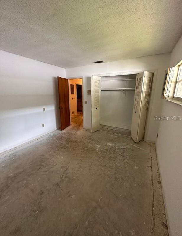 unfurnished bedroom featuring a textured ceiling and a closet