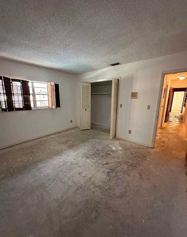 unfurnished bedroom featuring a closet, concrete flooring, and a textured ceiling