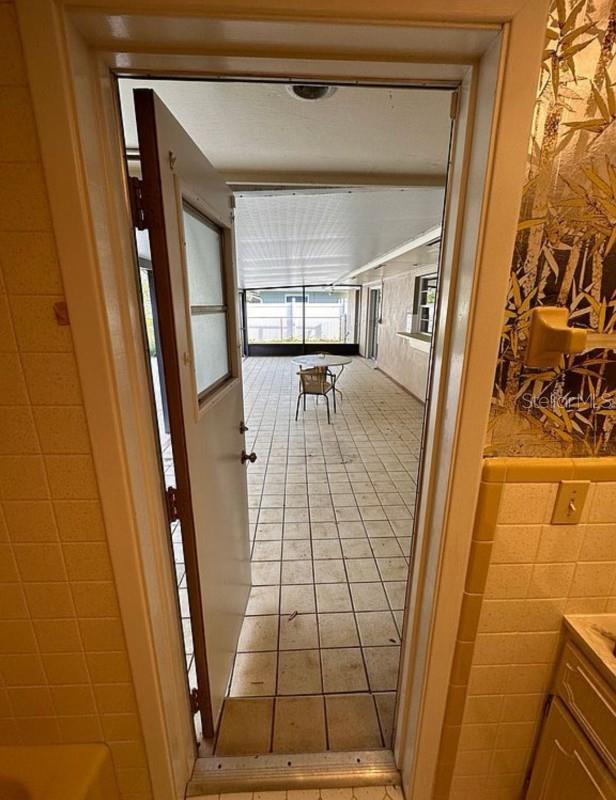 hallway featuring light tile patterned floors and tile walls