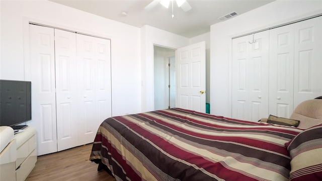 bedroom featuring hardwood / wood-style flooring, ceiling fan, and two closets