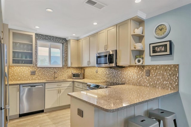 kitchen with light stone countertops, kitchen peninsula, sink, and appliances with stainless steel finishes