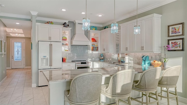 kitchen featuring stainless steel stove, white cabinetry, and high end fridge