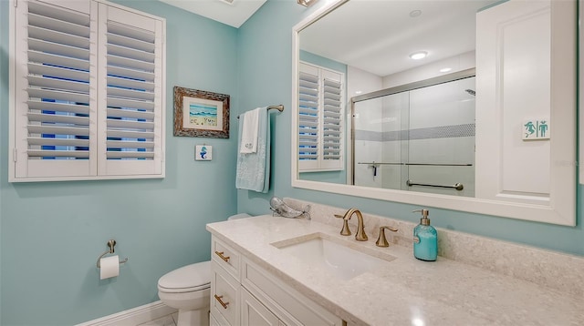 bathroom featuring a shower with door, vanity, and toilet