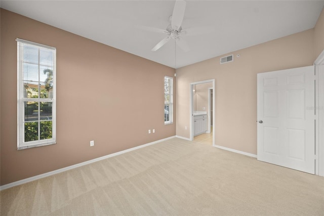 unfurnished bedroom featuring ensuite bath, ceiling fan, and light colored carpet