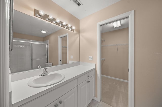 bathroom featuring tile patterned floors, vanity, toilet, and a shower with shower door