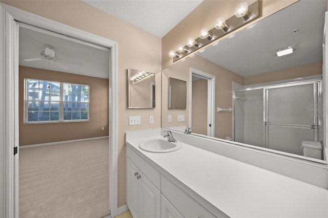 bathroom featuring ceiling fan, vanity, a shower with shower door, and toilet