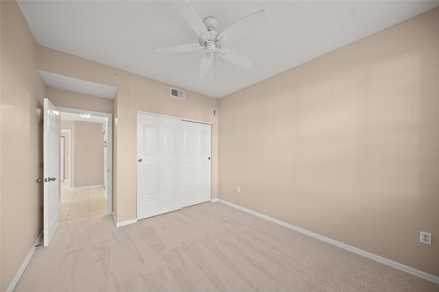 unfurnished bedroom with ceiling fan, a closet, and light colored carpet