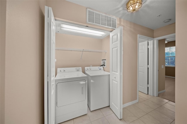 laundry room featuring washer and clothes dryer and light tile patterned floors