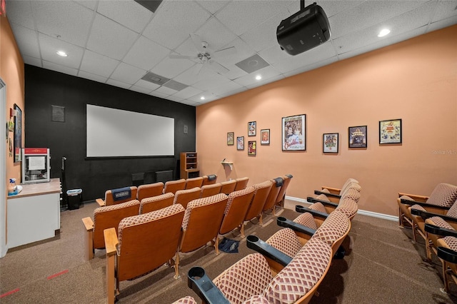 carpeted cinema room featuring ceiling fan and a drop ceiling