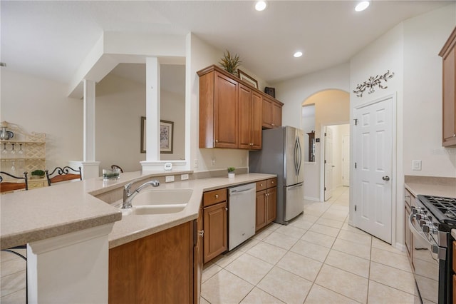 kitchen with kitchen peninsula, appliances with stainless steel finishes, a breakfast bar, sink, and light tile patterned flooring