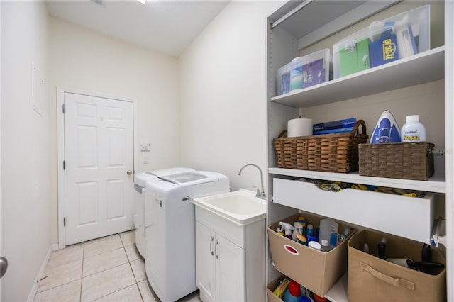 laundry room with cabinets, light tile patterned floors, separate washer and dryer, and sink