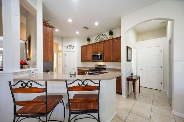 kitchen featuring visible vents, a breakfast bar, arched walkways, a peninsula, and appliances with stainless steel finishes