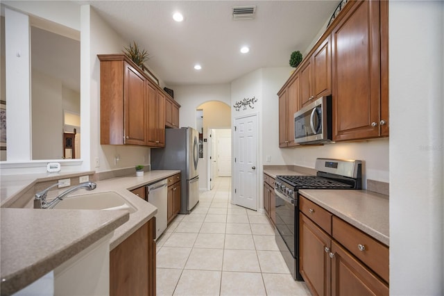 kitchen with visible vents, light tile patterned floors, arched walkways, stainless steel appliances, and a sink