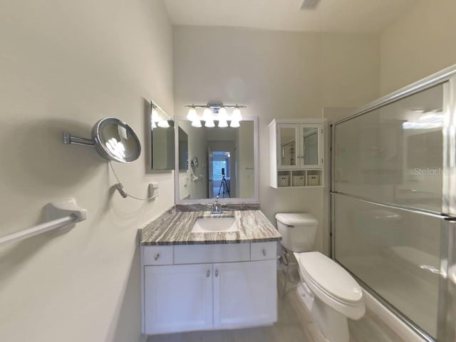 bathroom featuring an enclosed shower, vanity, and toilet