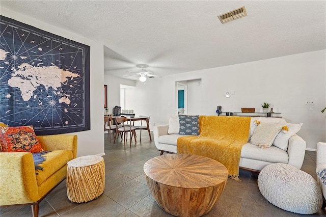 tiled living room with a ceiling fan, baseboards, visible vents, and a textured ceiling