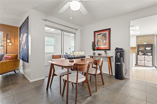 tiled dining space featuring ceiling fan, baseboards, and a textured ceiling