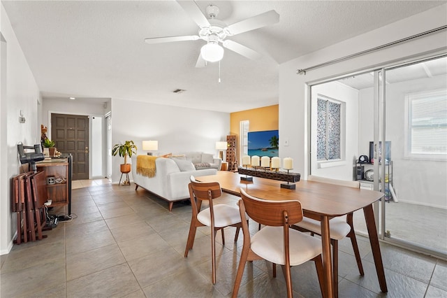 dining room featuring light tile patterned floors, visible vents, ceiling fan, a textured ceiling, and baseboards