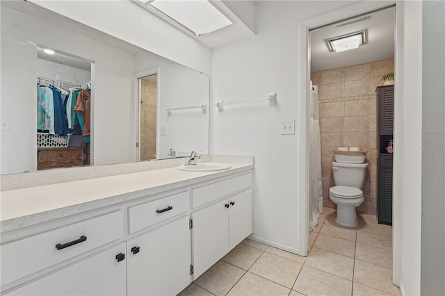 bathroom featuring tile patterned flooring, toilet, vanity, tile walls, and a walk in closet