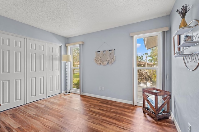 bedroom featuring a closet, a textured ceiling, baseboards, and wood finished floors