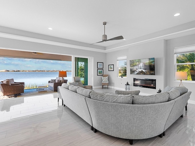 living room featuring a raised ceiling and ceiling fan