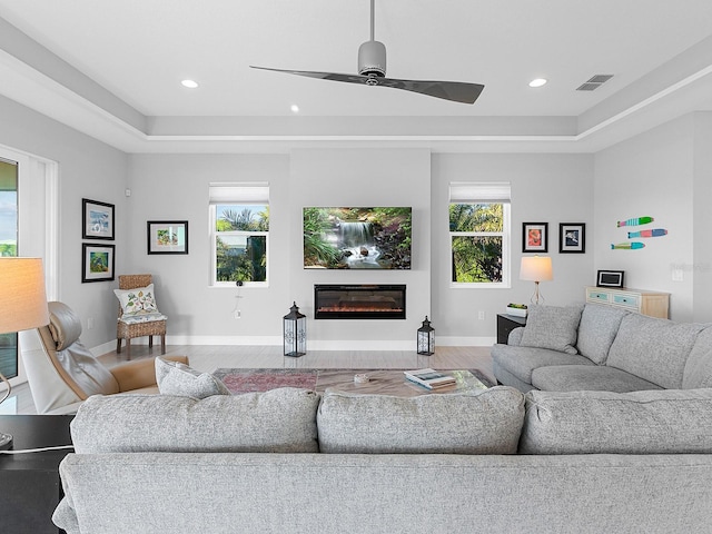 living room featuring hardwood / wood-style flooring, plenty of natural light, and a tray ceiling