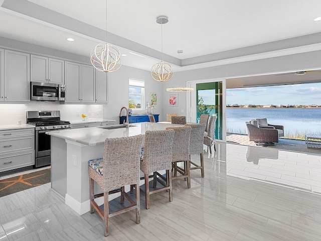 kitchen featuring a breakfast bar, appliances with stainless steel finishes, a water view, and a kitchen island with sink