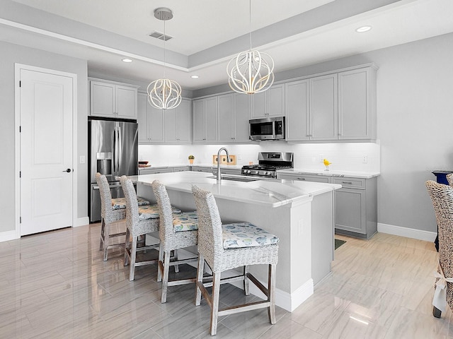 kitchen featuring a kitchen bar, stainless steel appliances, sink, a center island with sink, and an inviting chandelier